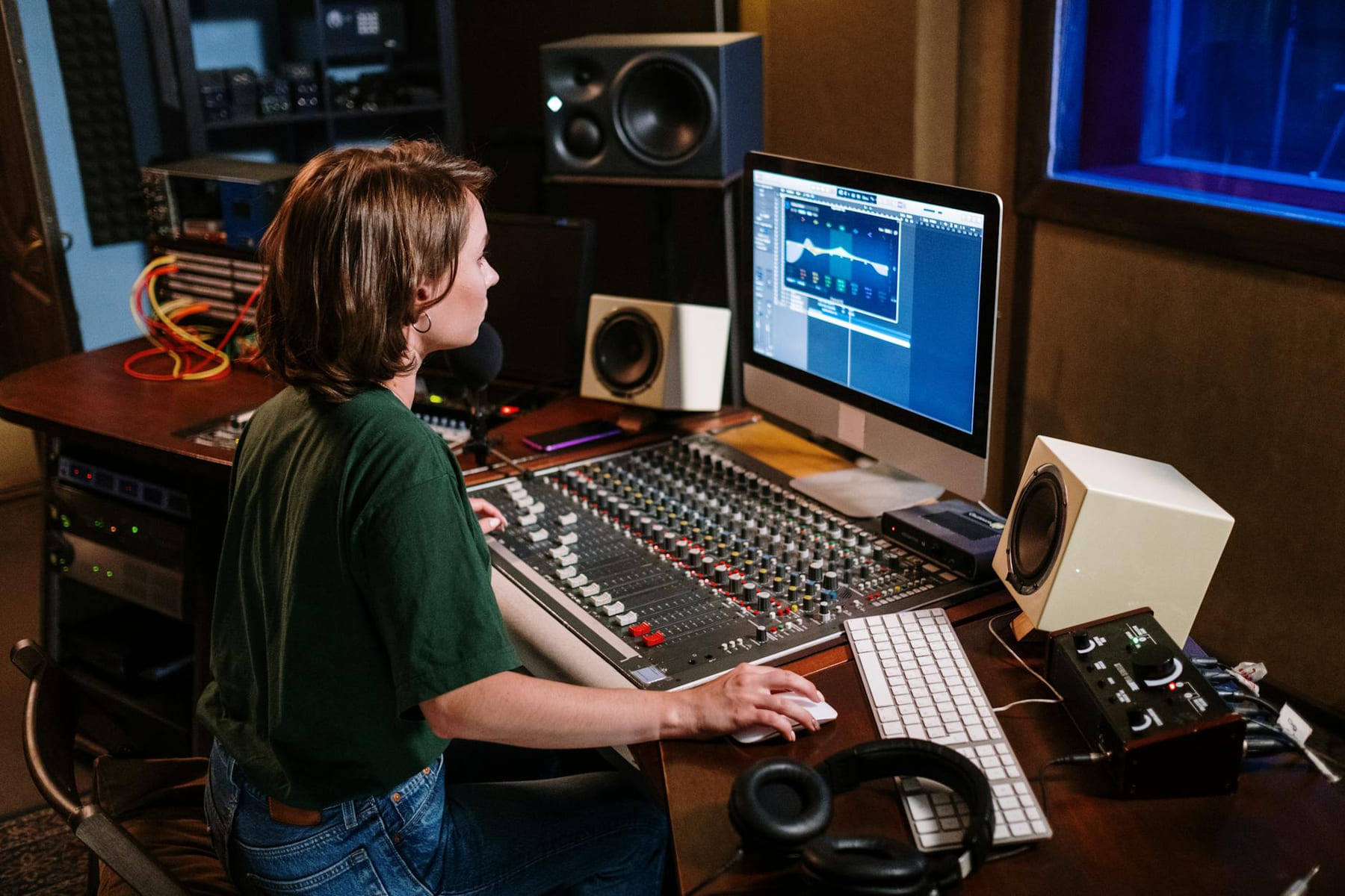 Woman in studio working on sound mixer and computer, focused on audio editing. on The Tech Shelf