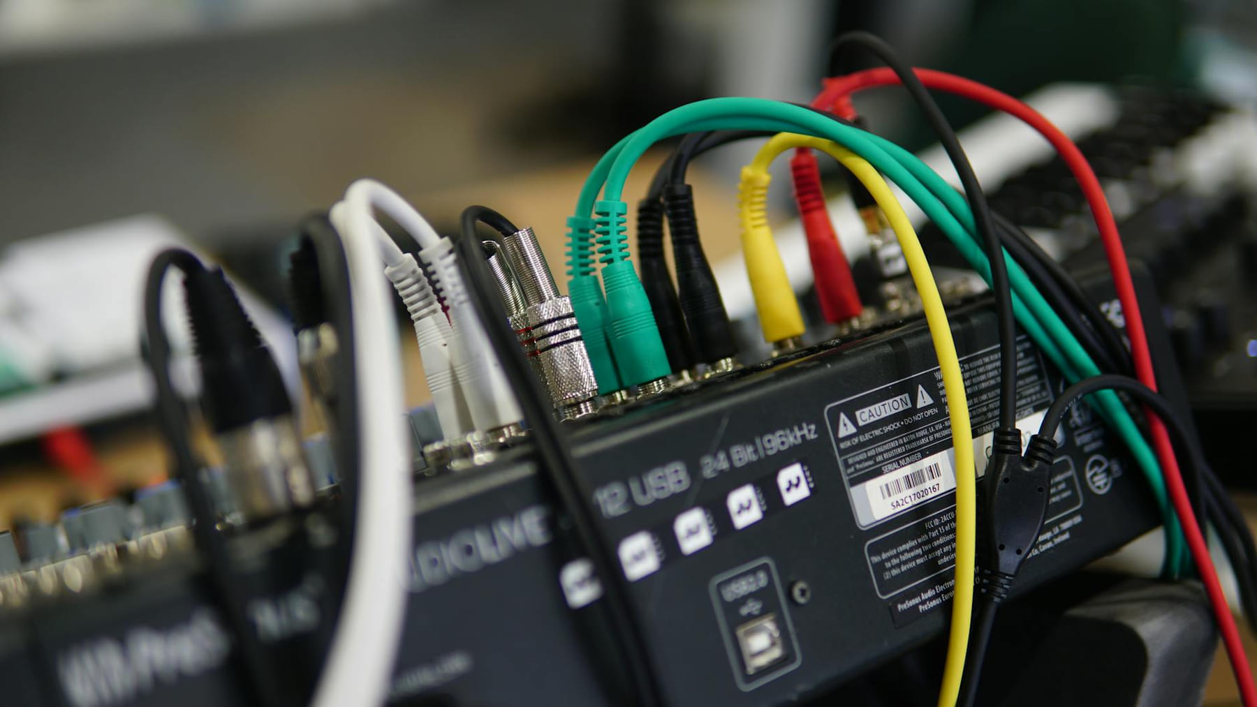 A detailed close-up image of multiple audio cables connected to a sound mixer, showcasing technology setup. on The Tech Shelf