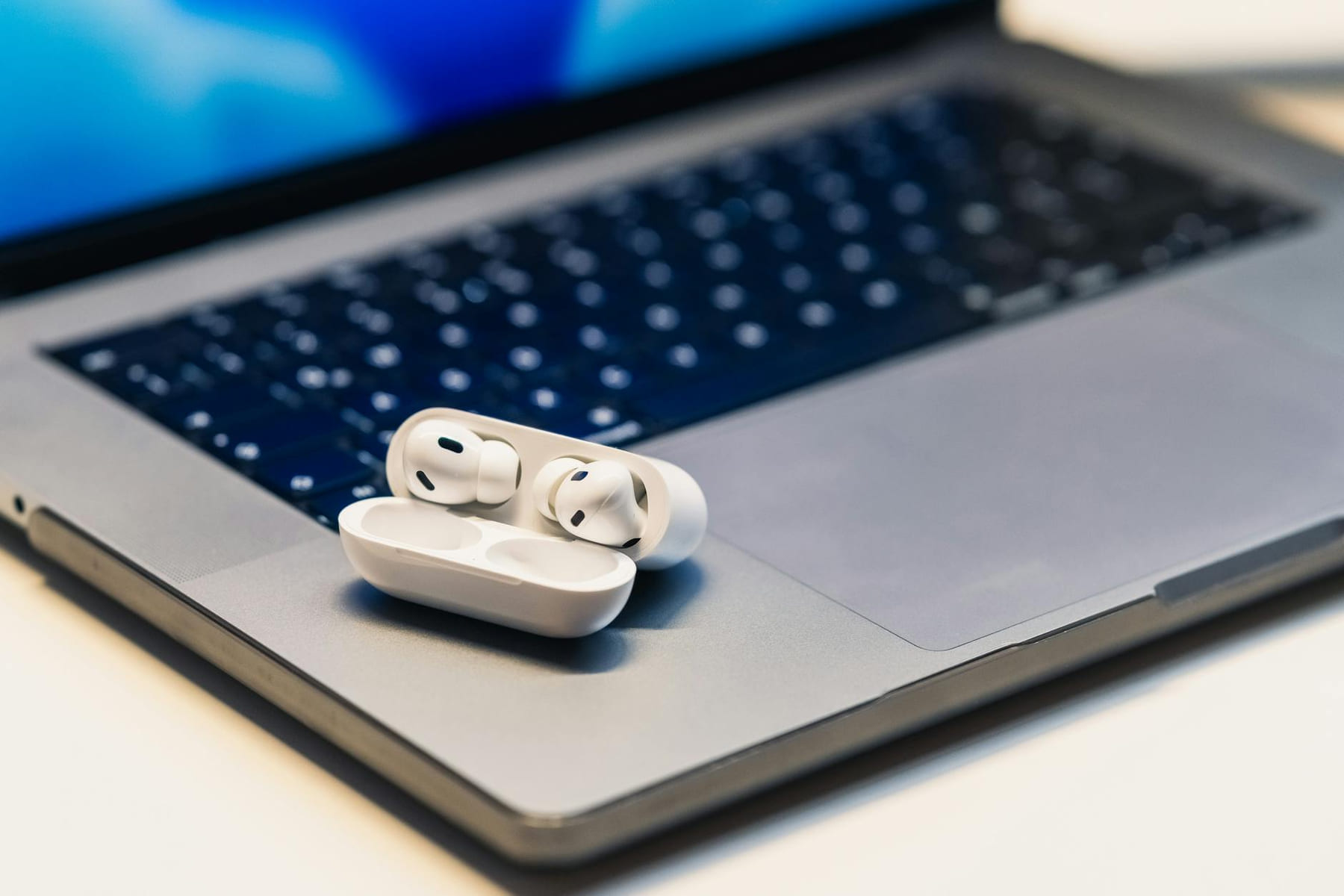 Close-up of wireless earbuds in case resting on an open laptop, highlighting modern technology. on The Tech Shelf