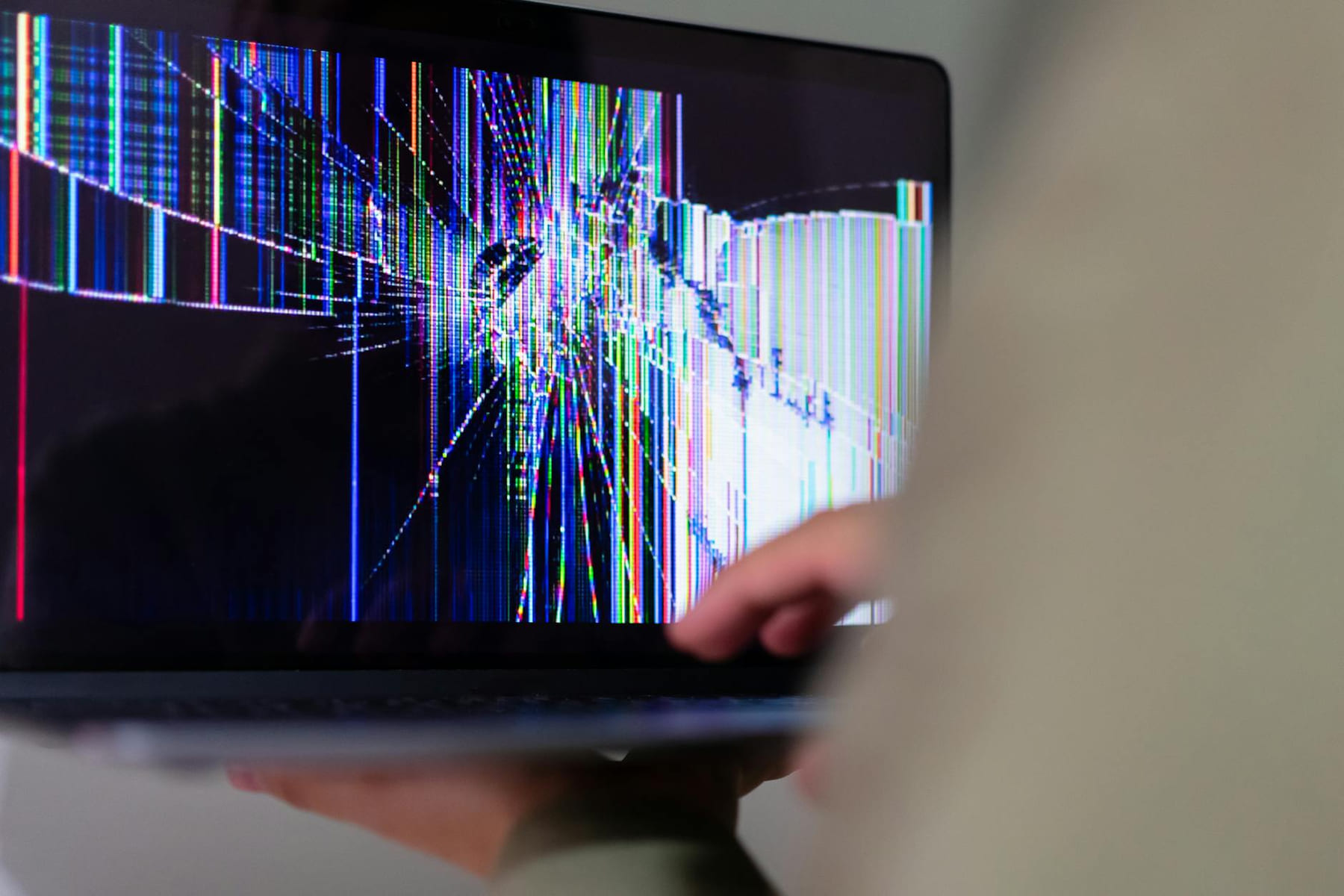 A close-up view of a cracked laptop screen displaying colorful digital distortion. on The Tech Shelf
