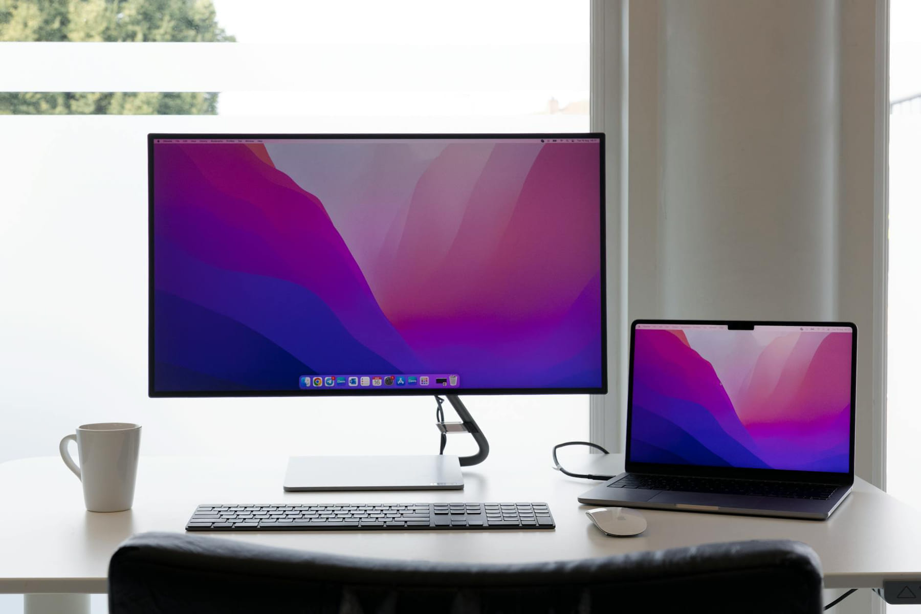 Minimalist workspace featuring dual monitors, keyboard, and a laptop on a clean desk. on The Tech Shelf