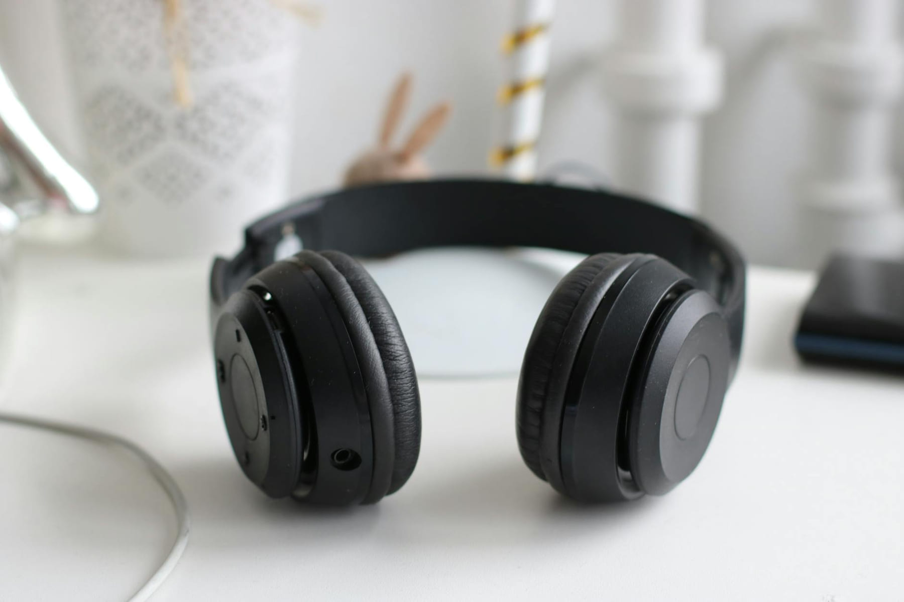 Close-up of black wireless headphones on a white desk in a modern setting. on The Tech Shelf
