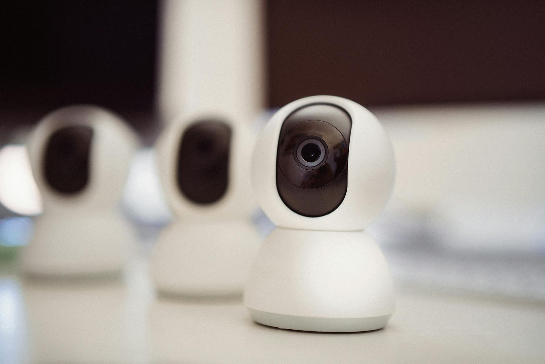 Close-up of three smart home security cameras placed on a white desk indoors. on The Tech Shelf