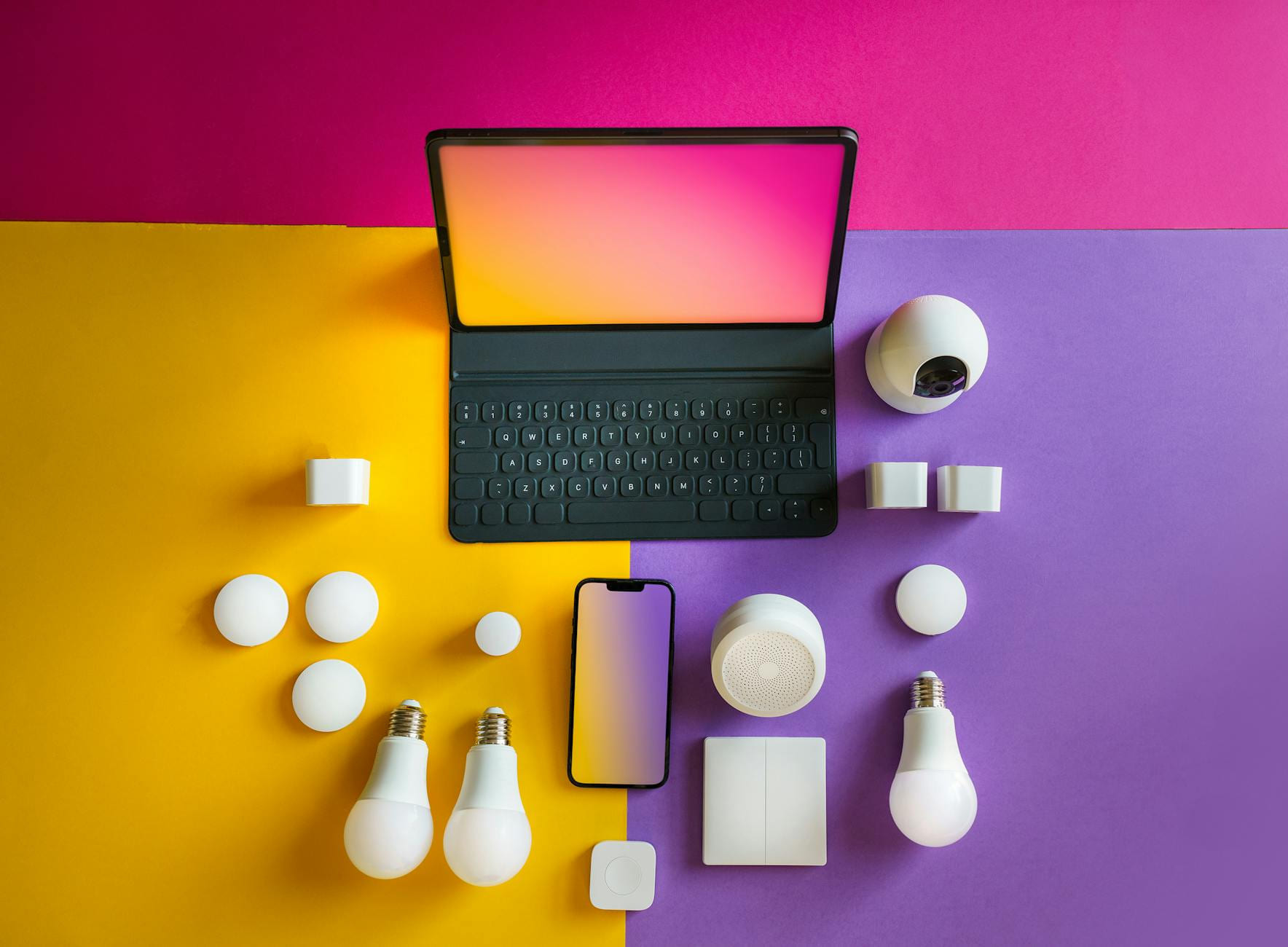 Flat lay of smart home devices including a tablet, smartphone, and bulbs on a vibrant background. on The Tech Shelf