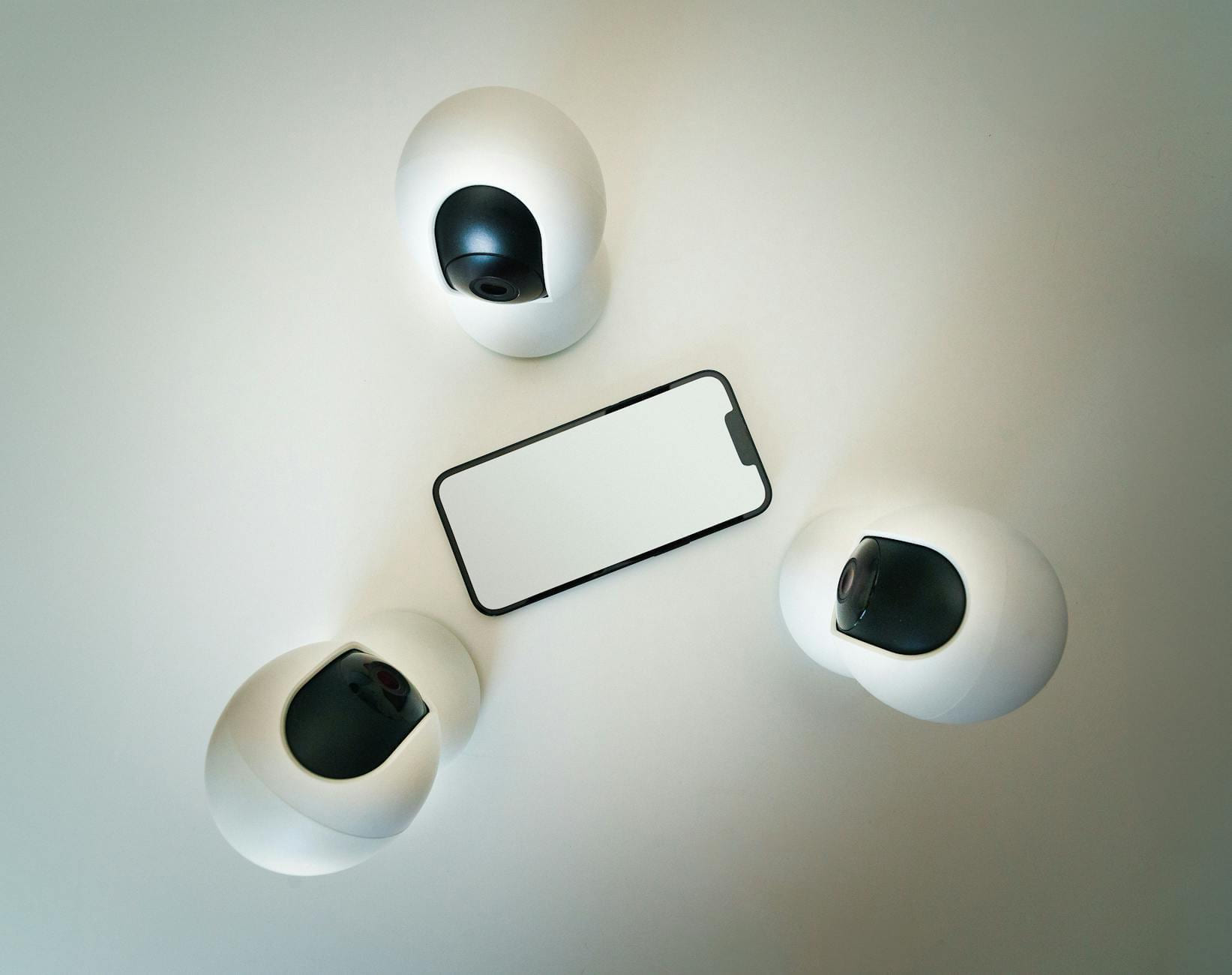 Smartphone surrounded by security cameras on a modern, minimalist setup. on The Tech Shelf